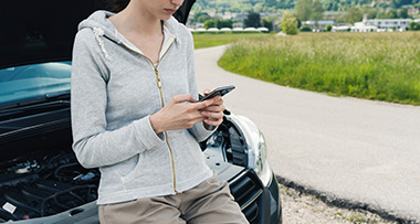 a woman using her phone while waiting for breakdown recovery
