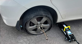 a white car having its flat tire replaced