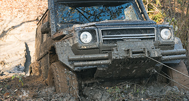 an SUV being winched out of a muddy decline with a row rope